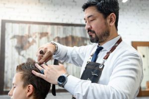 Барбер стрижет волосы клиенту